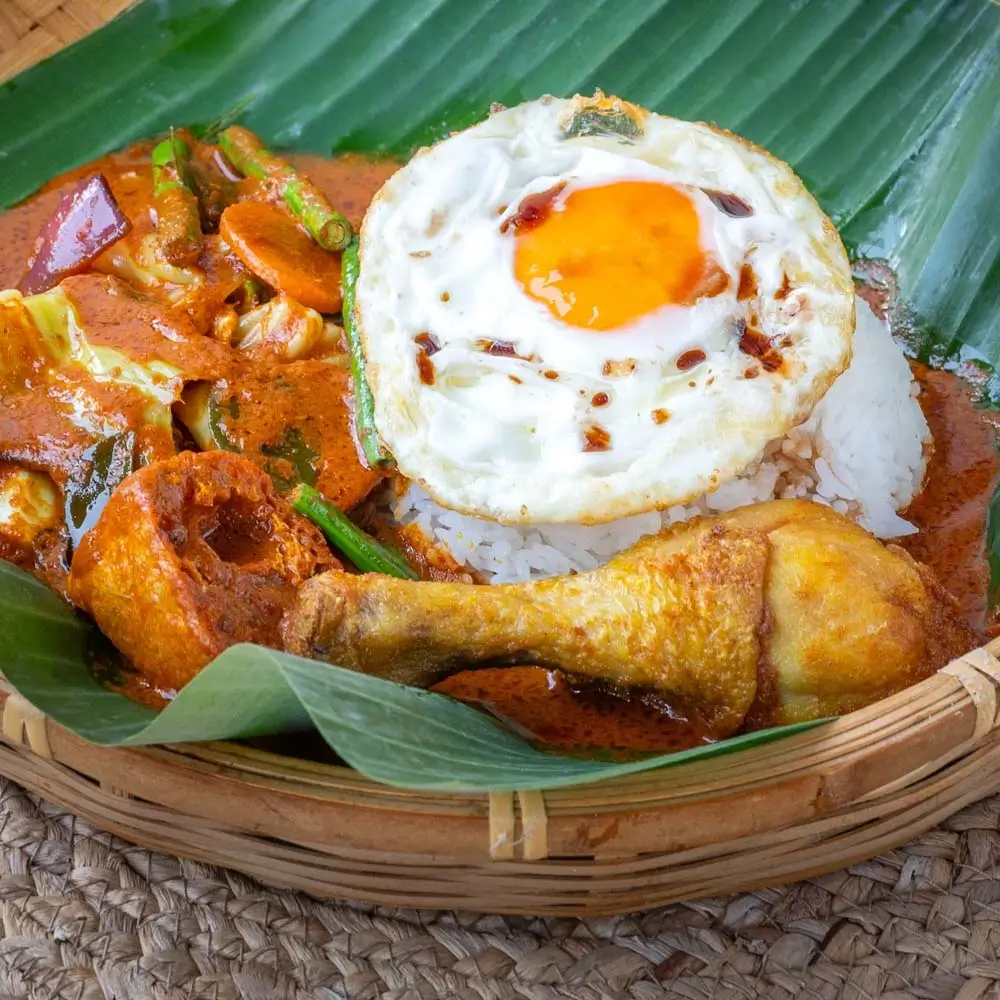 Traditional nasi banjir ayam penyet featuring flattened chicken, fried egg, steamed rice in chcicken curry gravy
