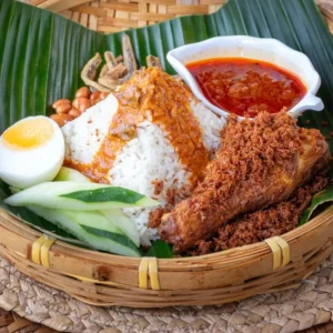 Nasi lemak ayam pop with coconut rice, crispy fried chicken, boiled egg, and fried anchovies on banana leaf