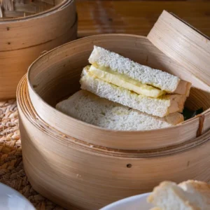 Roti kukus kaya butter with steamed white bread filled with coconut jam and butter in bamboo steamer.