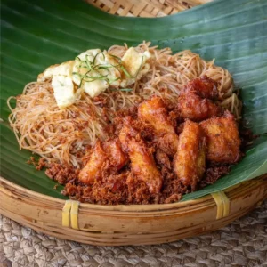 Mee siam ayam pop with crispy fried filet chicken, rice vermicelli, and thinly sliced fried egg served on banana leaf