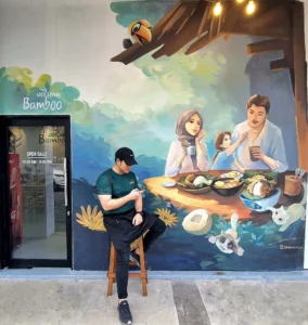 Nasi lemak bamboo restaurant entrance with colorful Malaysian family dining mural and hornbill bird artwork